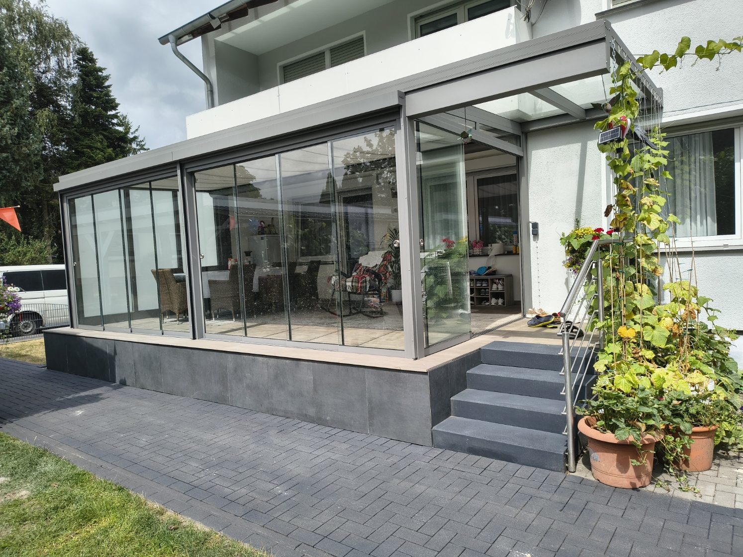 Terrassenbau Ahaus – moderne Terrasse mit Glasanbau und Natursteinplatten