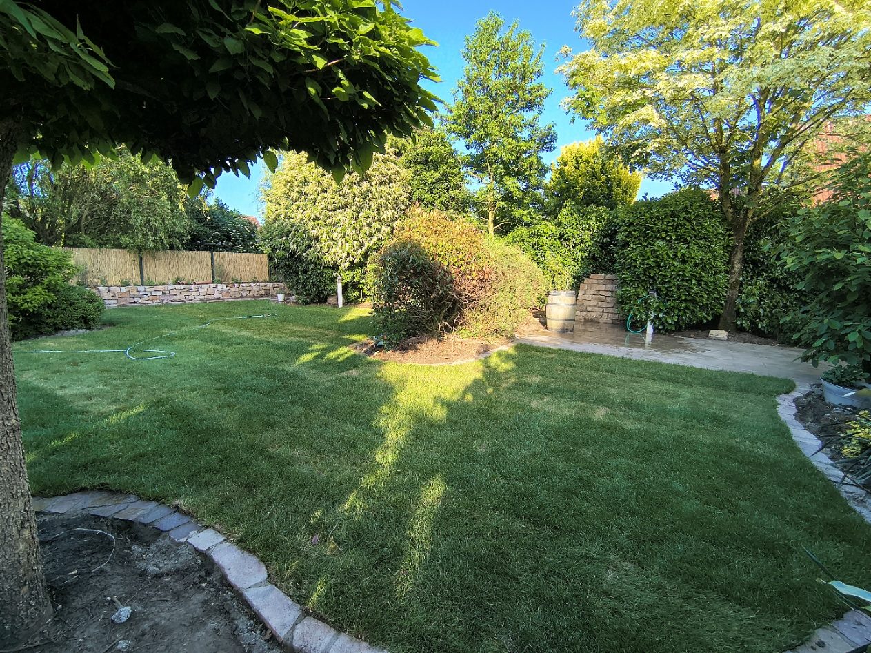 Gartengestaltung Ahaus – Garten mit Rasen, Natursteinmauer und Terrasse